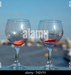 Deux verres vides avec un morceau de fraise dans chaque sur le côté gauche de la Tower Bridge, enjambant la rivière Thames, London, England, UK. Banque D'Images