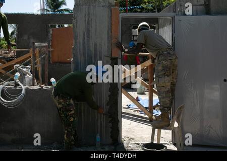Circuit de l'armée américaine. Desmond Dake, droite, et Philippine Air Force aérienne du 2e classe Ladaran Wilbert, gauche, utiliser le mortier pour combler un écart important entre un mur et porte dans la PAGASA, Bataan, Philippines, pour une nouvelle salle de classe dans le cadre de l'exercice Balikatan, 26 mars 2019. Deux nouvelles salles de classe sont construites avec les efforts combinés de l'armée américaine et l'AFP Air Force. Balikatan est un exercice d'entraînement militaire organisé par les Philippines entre l'AFP et de militaires américains, ainsi que des participants de l'Australian Defence Force. Dake, un natif de Houston, au Texas, est un ingénieur de génie de combat avec 561 E S Banque D'Images