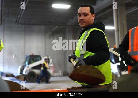 Airman Senior Ray Brigante, 319e Escadron de génie civil de la gestion des opérations, des pelles de compagnon du sable dans un entonnoir au cours d'une réserve de sacs de bénévolat le 28 mars 2019, à Grand Forks, Dakota du Nord. Les membres de base et les pompiers locaux ont été parmi les bénévoles qui ont travaillé de concert pour créer des sacs de 10 000 pour la ville de Grand Forks en prévision d'une inondation prévu au printemps. Banque D'Images