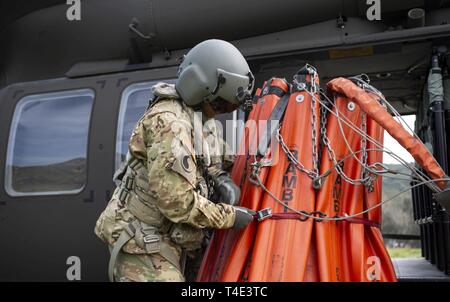 L'Adjudant-chef de l'armée américaine Douglas 2 Martine, une normalisation de la Californie pilote de la Garde nationale de l'Armée de la Compagnie Bravo, 1er Bataillon d'hélicoptères d'assaut, 140e Régiment d'aviation, cinches un seau avant de le charger sur un Black Hawk UH-60M hélicoptère à Irvine Lake dans le comté d'Orange, en Californie, le 19 mars 2019, lors d'un vol d'entraînement. Le vol a donné l'occasion aux pilotes de familiarisation pratique et godet en vol avec des charges externes. Banque D'Images