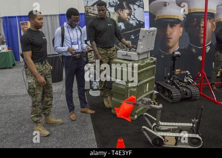 Le sergent des Marines. Jeremy McBroom et le sergent. Steven Bellamy, techniciens des explosifs et munitions pour la 2e Compagnie de NEM, 8e Bataillon de soutien du génie, de discuter avec des robots Erondu Chigozie NEM, un étudiant à l'Université George Mason, lors d'une Société Nationale des Ingénieurs Noir salon de l'emploi conférence à Detroit, Michigan, le 29 mars 2019. NSBE organise son 45e congrès national annuel composé de différents programmes et d'ateliers qui sont conçus pour profiter à l'école primaire, collégial, technique, professionnel et les participants internationaux et le Corps des Marines est une organisation partenaire. Marin Banque D'Images