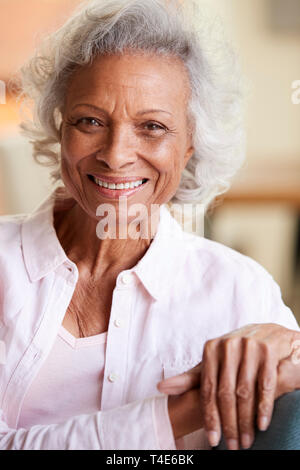 Portrait Of Smiling Senior Woman Relaxing On Sofa At Home Banque D'Images