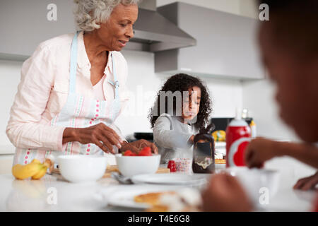 Grand-mère en cuisine avec petits-enfants faire des crêpes ensemble Banque D'Images