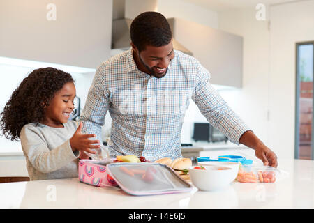 Fille dans la cuisine à la maison d'aider le Père à faire des paniers-repas. Banque D'Images