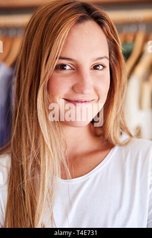 Portrait of Female Client ou le propriétaire par permanent Racks de vêtements en boutique de mode indépendant Banque D'Images