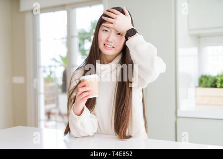 Belle asiatique Femme buvant un café dans une tasse de papier à emporter a souligné avec la main sur la tête, choqué de honte et de surprise, de colère et de frustration face Banque D'Images