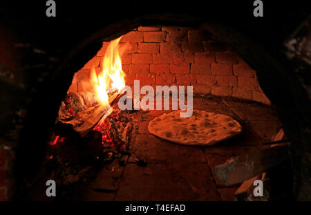 La pâte à pizza d'être cuits au four à pizza au feu de bois Banque D'Images