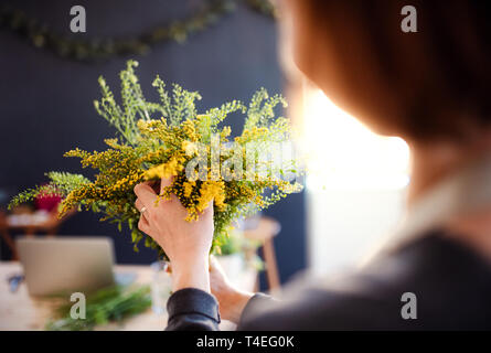 Un portrait de jeune femme créative l'organisation de fleurs dans un magasin de fleur. Un démarrage de fleuriste entreprise. Vue arrière. Banque D'Images