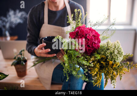 Un portrait de jeune femme créative avec une organisation de fleurs dans un magasin de fleur. Un démarrage de fleuriste entreprise. Banque D'Images