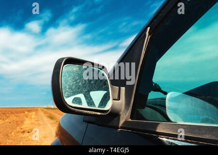 Miroir de l'aile d'une voiture sur la saleté route de campagne et après-midi d'été ensoleillé Banque D'Images