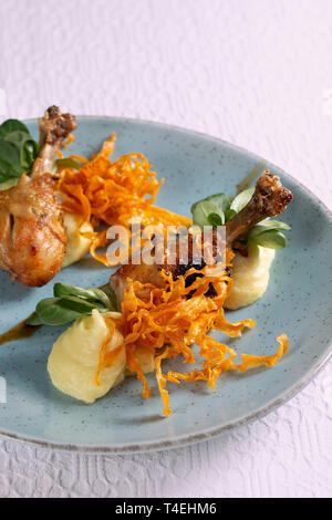 Cuisses de poulet rôti aux épices, avec une purée de pommes de terre et de pommes de terre croustillantes sur une plaque Banque D'Images