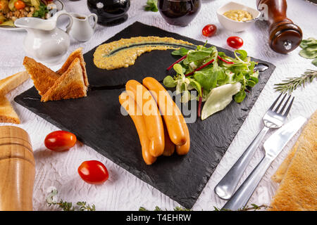 Bouillir les saucisses de Francfort à la moutarde, salade et toast sur ardoise board Banque D'Images