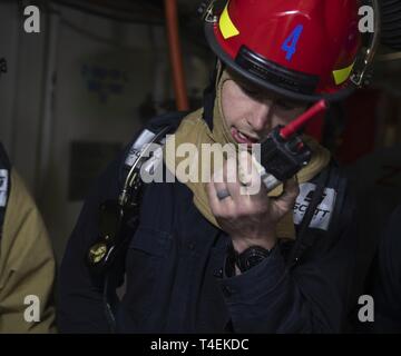 NEWPORT NEWS, Virginie (27 mars 2019) Dommage Controlman 2e classe Brandon Carric, de Palm Springs, Californie, affectés à l'USS Gerald R. Ford (CVN 78) Département de génie, utilise une radio pour transmettre l'information au cours d'un exercice de contrôle des dommages. Ford est actuellement en post-shakedown la disponibilité de Huntington Ingalls Industries-Newport News Shipbuilding. Banque D'Images