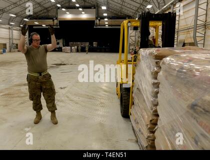 Les cadres supérieurs de l'US Air Force Airman Cody de suite, antenne mobile pour porter le 435ème Groupe d'intervention d'urgence, Base aérienne de Ramstein, en Allemagne, en ce moment au Camp Lemonnier, Djibouti, des groupes de soutien de l'Afrique (Force-Horn CJTF-HOA), guides d'un opérateur de chariot élévateur de palettes transport des aliments Agence des États-Unis pour le développement international (USAID) au Camp Lemonnier, 31 mars 2019, pour le ministère américain de la Défense (DoD) des secours humanitaires dans la République du Mozambique et ses environs après le cyclone Idai. Les équipes de GFIM HOA, qui mène les secours humanitaires DoD effo Banque D'Images