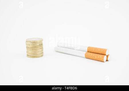 Plusieurs cigares et une pile de pièces sur fond blanc. Concept de dépenses économiques sur la consommation de tabac. Banque D'Images