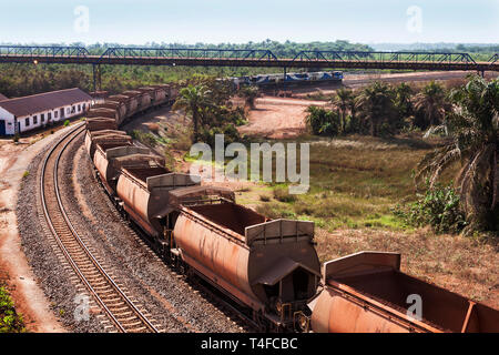 Opérations portuaires et ferroviaires pour la gestion et le transport du minerai de fer. Train sur rail boucle sous la courroie du convoyeur de chargement après la décharge, avec wagons vides Banque D'Images