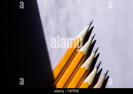 Cinq crayons simple sur un solide fond violet dans la lumière du soleil dure lumière contrastée de la fenêtre avec une copie de l'espace. Banque D'Images