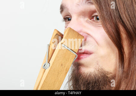 Homme avec clip clothespin peg sur son nez. Jeune brun sentiment désagréable odeur. Mauvaise odeur concept. Banque D'Images