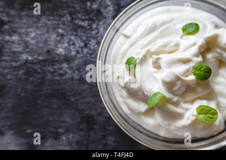 Pâte crémeuse au yogourt à la crème à la menthe dans un bol sur une sombre rétro arrière. Vue d'en haut Banque D'Images