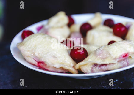 Quenelles avec les cerises dans un plat sur une sombre rétro arrière Banque D'Images