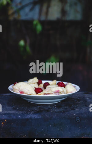 Quenelles avec les cerises dans un plat sur une sombre rétro arrière Banque D'Images