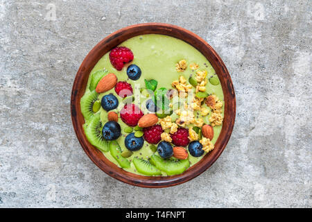 Bol à thé matcha smoothie vert avec des fruits, baies, céréales, noix et graines. petit-déjeuner végétalien sain. Vue de dessus Banque D'Images