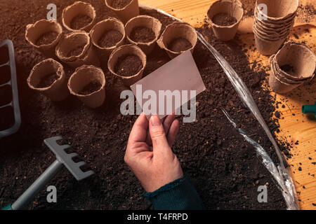 Gardener holding blank business card mock up au-dessus de l'agriculture biologique et de l'équipement de jardinage Banque D'Images