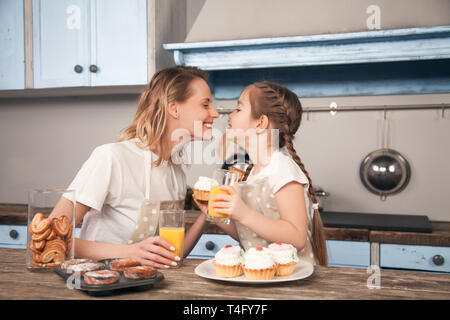 Heureux famille aimante dans la cuisine. Mère et enfant fille fille mangent des cookies qu'ils ont fait et d'avoir du plaisir dans la cuisine. Cuisine maison Banque D'Images