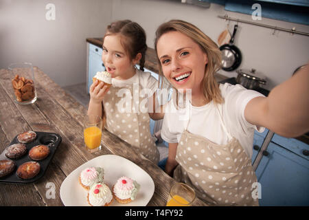 Heureux famille aimante dans la cuisine. Mère et enfant fille fille mangent des cookies qu'ils ont fait et d'avoir du plaisir dans la cuisine. Cuisine maison Banque D'Images