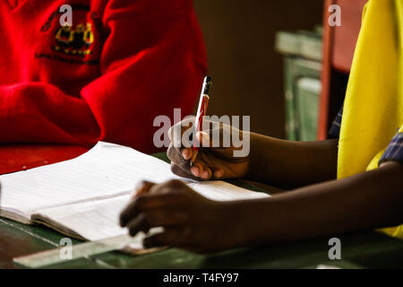 Photo en gros plan des mains de l'enfant tenant un crayon et écrire les nouvelles informations sur la leçon à l'école. Du papier propre à l'ordinateur portable. Les étudiants Banque D'Images