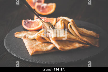 Crêpes Suzette avec des tranches d'orange sanguine sur le conseil de pierre noire Banque D'Images