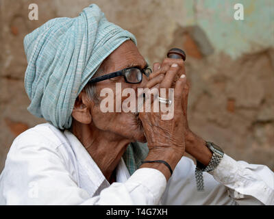 Vieil indien homme Rajasthani fume du tabac dans sa pipe chillum. Banque D'Images