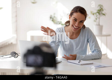 Belle femme souriante en agitant sa main looking at camera Banque D'Images