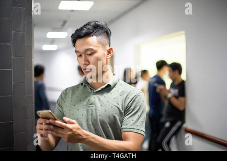 Beaux hommes asiatiques se concentrant sur smartphone | message de frappe on cellphone Banque D'Images