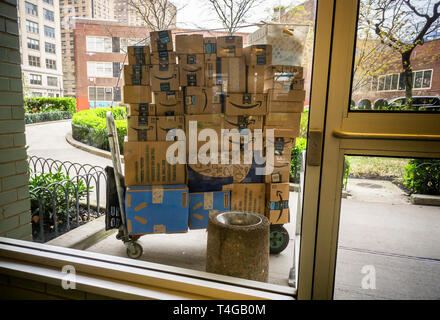 Un livreur avec son chariot chargé d'achats, principalement Amazon, offre à un immeuble le quartier de Chelsea, New York le Dimanche, Avril 14, 2019 . (© Richard B. Levine) Banque D'Images