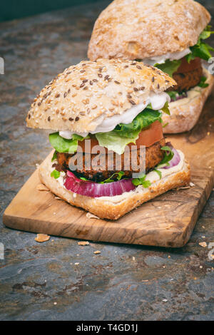 Vegan burgers sur une carte sur ardoise en bois d'olivier Banque D'Images