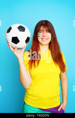 Femme est socccer en fan t-shirt jaune avec ballon de soccer Banque D'Images