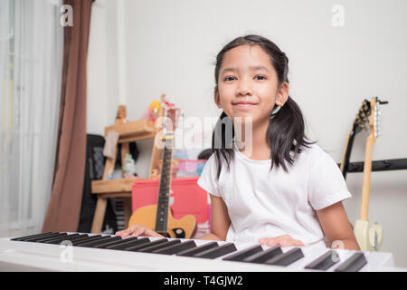 Petite fille asiatique d'apprendre à jouer d'un clavier de piano synthétiseur avec bonheur, Thai girl l'étude de la musique à la maison Banque D'Images