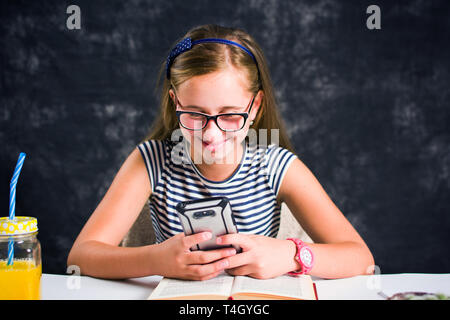 Happy teen girl looking at son téléphone et souriant Banque D'Images