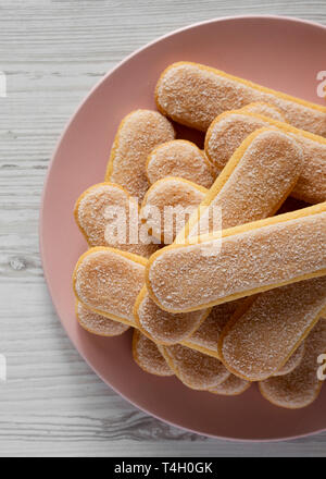 Savoyardi les cookies ou biscuits Doigts de dame rose sur plaque sur fond de bois blanc, vue du dessus. Mise à plat, les frais généraux, d'en haut. Close-up. Banque D'Images