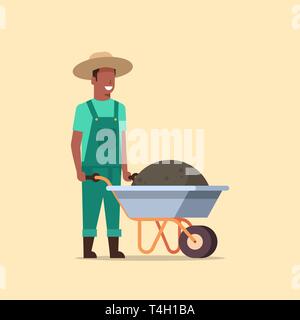 Homme jardinier poussant brouette pleine de terre compost african american agriculteur travaillant dans le port jardin jardinage salopette pleine longueur concept Illustration de Vecteur