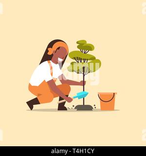 La productrice de planter les jeunes arbres african american woman jardinier creuser travail de la terre en jardin jardinage télévision agricole concept pleine longueur Illustration de Vecteur