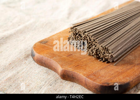 Nouilles soba sarrasin séché sur planche de bois rustique, vue de côté. Close-up. Banque D'Images