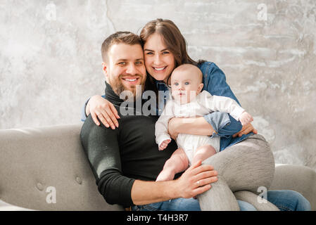 Famille heureuse avec bébé s'asseoir à canapé Banque D'Images