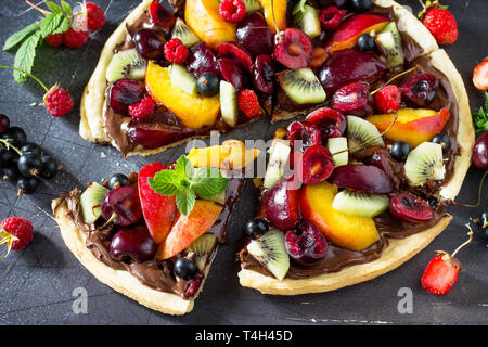 La vitamine dessert. Des délicieux fruits d'été pizza avec pâte de chocolat petits fruits sur une table en pierre. Banque D'Images