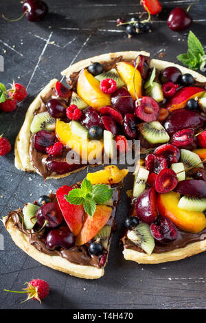 La vitamine dessert. Des délicieux fruits d'été pizza avec pâte de chocolat petits fruits sur une table en pierre. Banque D'Images