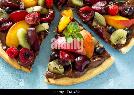 La vitamine dessert. Des délicieux fruits d'été pizza avec pâte de chocolat petits fruits sur une table en pierre bleue. Banque D'Images