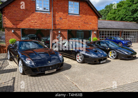 Plusieurs voitures de sport Ferrari de couleur sombre dont une Ferrari 599 GTB stationné à l'extérieur de Meridien Modena, Lyndhurst, Hampshire, Royaume-Uni. Banque D'Images