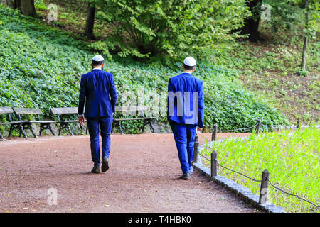 2 jeunes hommes, les juifs hassidiques en costumes bleus et bouchon blanc à pied à Ouman. L'Ukraine, le Nouvel An juif. Banque D'Images