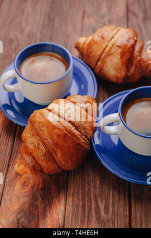 Deux tasses de café chaud et des croissants sur un fond de bois, la bonne lumière, atmosphère du matin Banque D'Images